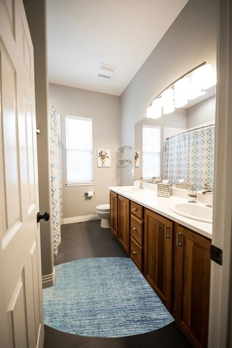 HomeRoots 4' Ivory and Blue Round Abstract Power Loom Area Rug in Wooden and Grey Bathroom