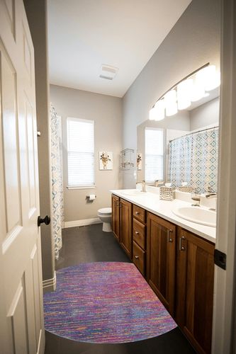 HomeRoots 4' Blue and Pink Round Abstract Power Loom Area Rug in Wooden and Grey Bathroom